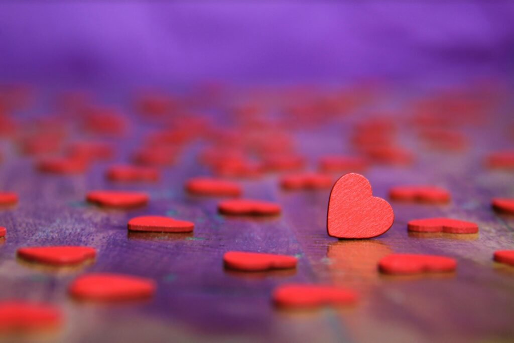 Red wooden hearts on a vibrant purple surface, symbolizing love.