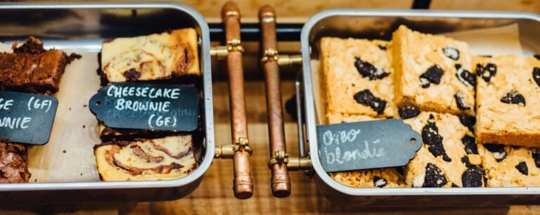 A tempting display of gluten-free brownies and blondies in trays, perfect for dessert lovers.