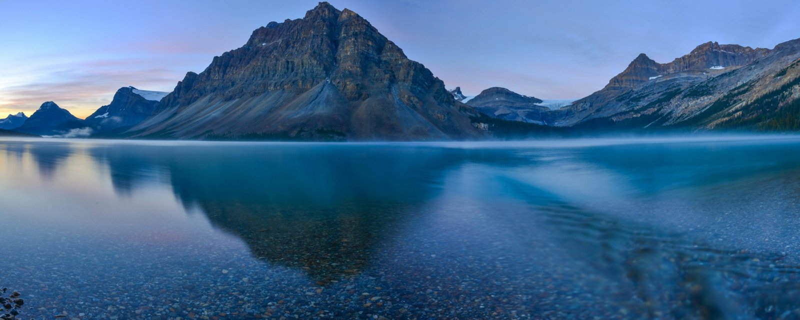 Beautiful sunrise reflection at Bow Lake with towering mountains in Banff National Park.