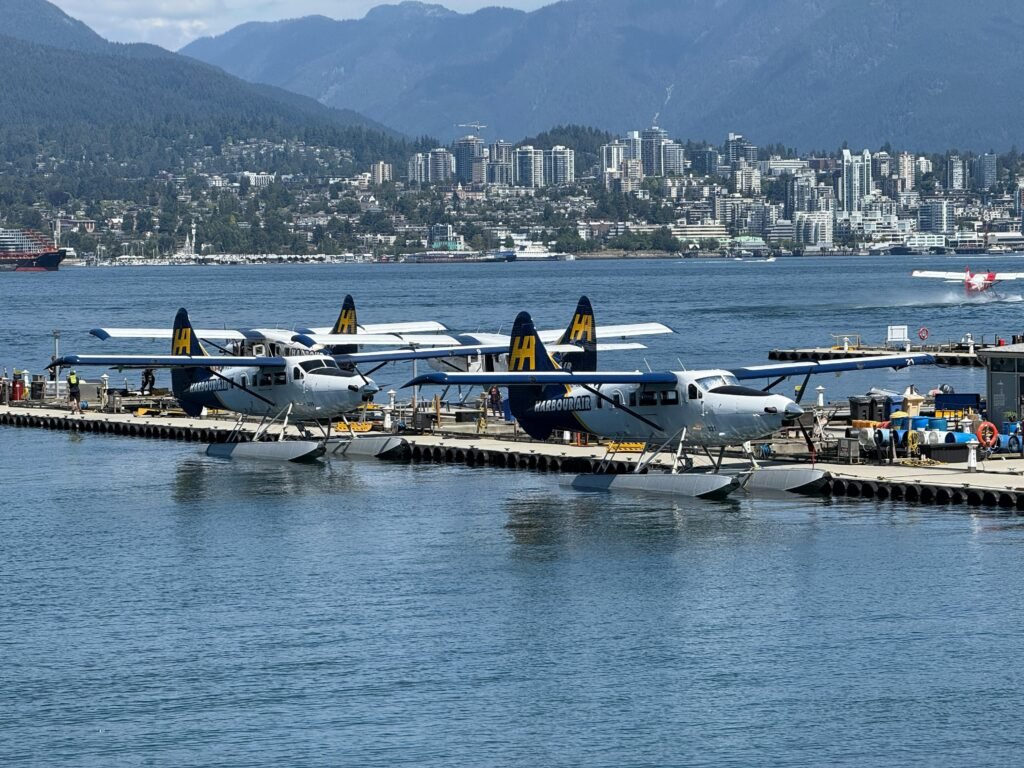 Seaplanes docked at Vancouver waterfront with city skyline in background.