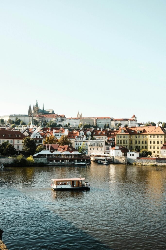 Beautiful view of historic Prague and the Vltava River with a small boat, showcasing Czech architecture.