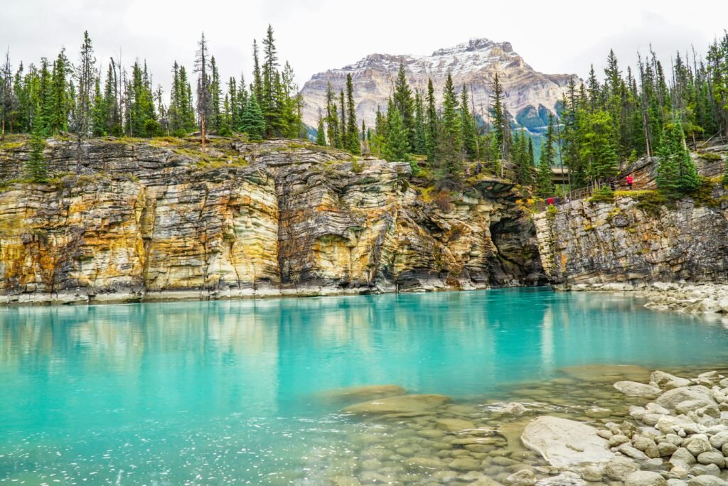 Vibrant turquoise waters of Maligne Canyon in Jasper National Park, surrounded by rocky cliffs and pine trees.