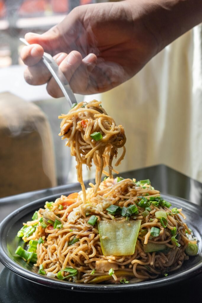 Delicious stir-fried noodles topped with fresh vegetables served hot, highlighting Asian cuisine.