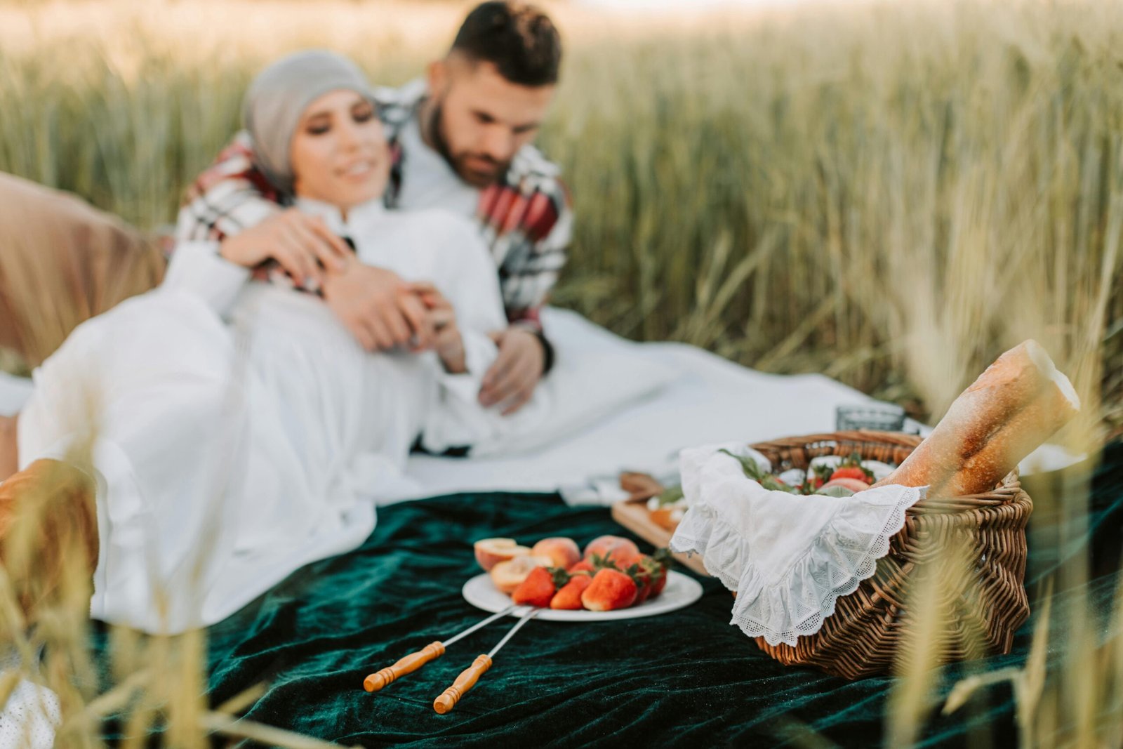 Couple enjoying a picnic in a wheat field, sharing a romantic moment.