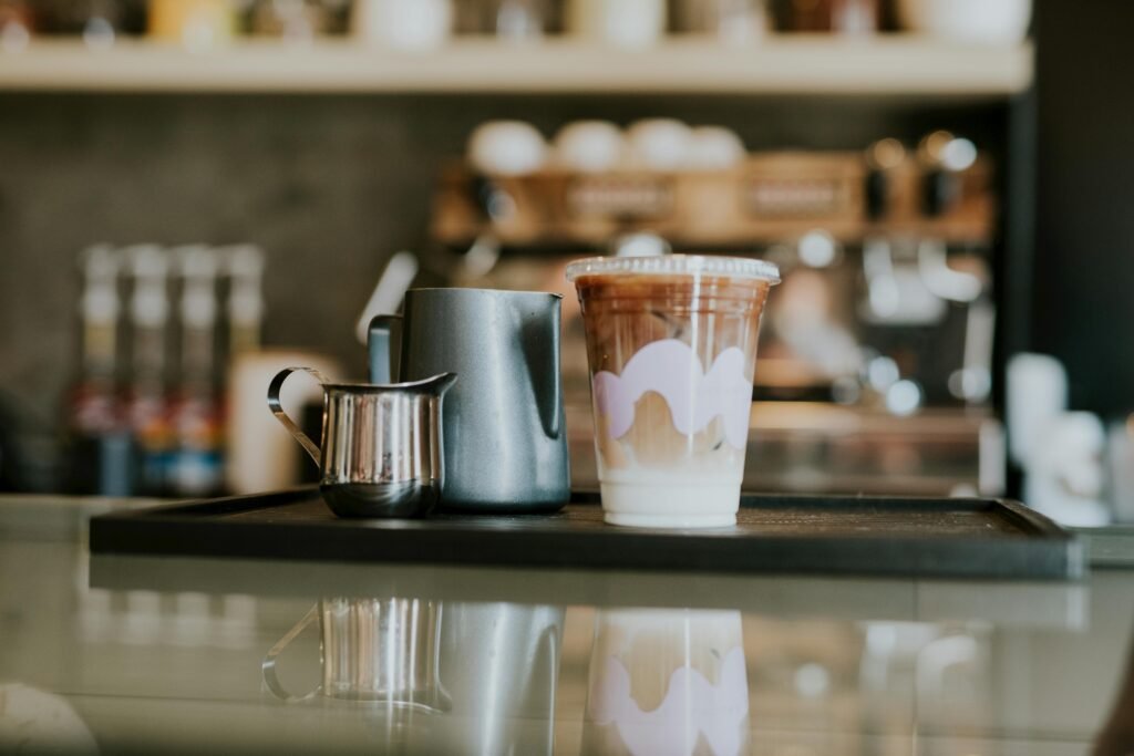Iced coffee on a café counter with styled cups and creamers, perfect for beverage lovers.