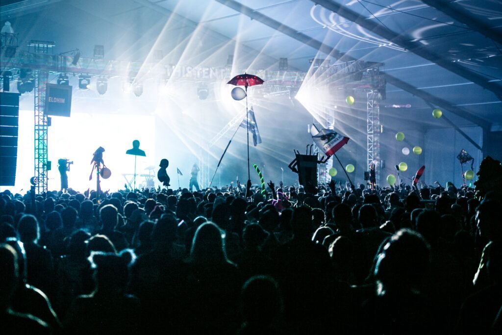 A dynamic crowd enjoying a live concert with bright stage lights and festive decorations.