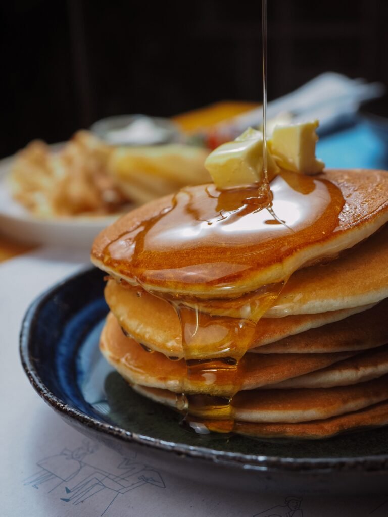 Close-up of golden pancakes with syrup and butter, perfect for a breakfast meal.