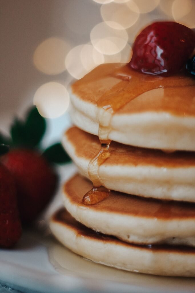 A close-up of a pancake stack with syrup and berries, captured with a warm, inviting ambiance.