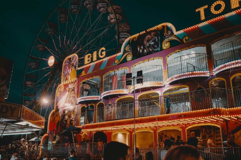 A lively scene at an amusement park with a ferris wheel and colorful lights at night.