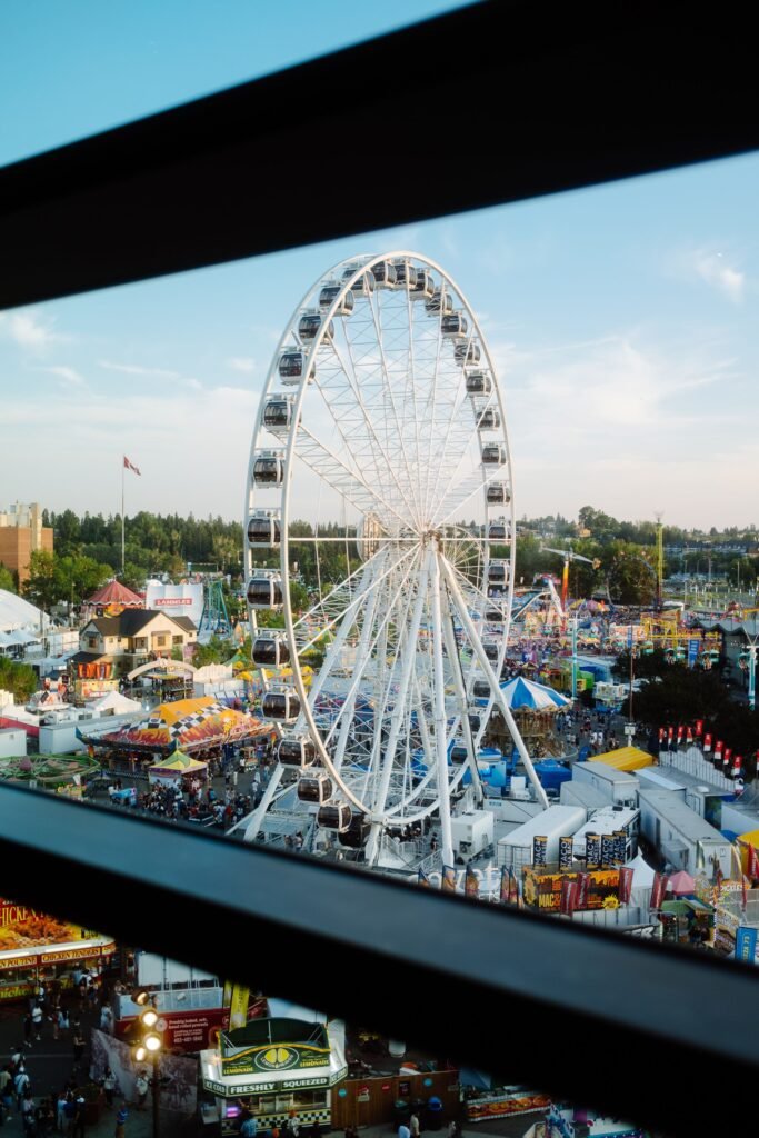 Aerial view of a bustling fairground with a prominent Ferris wheel under a clear sky.