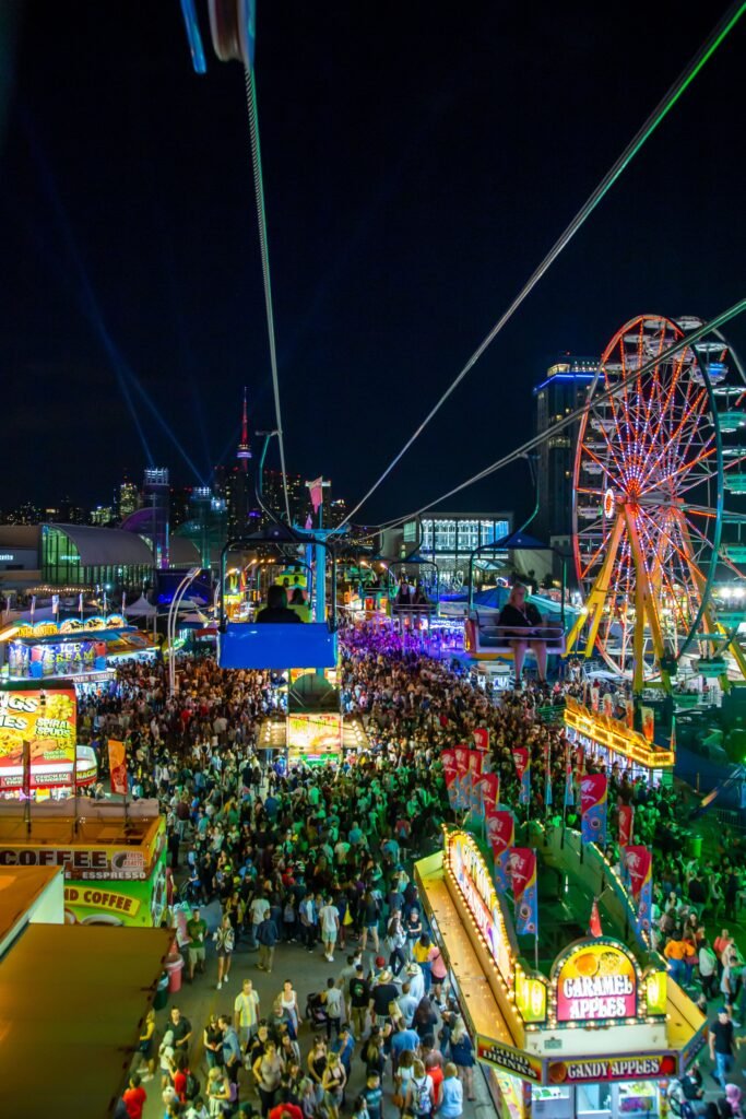 From above of ropeway near observation wheel and crowd of unrecognizable travelers walking on street in twilight