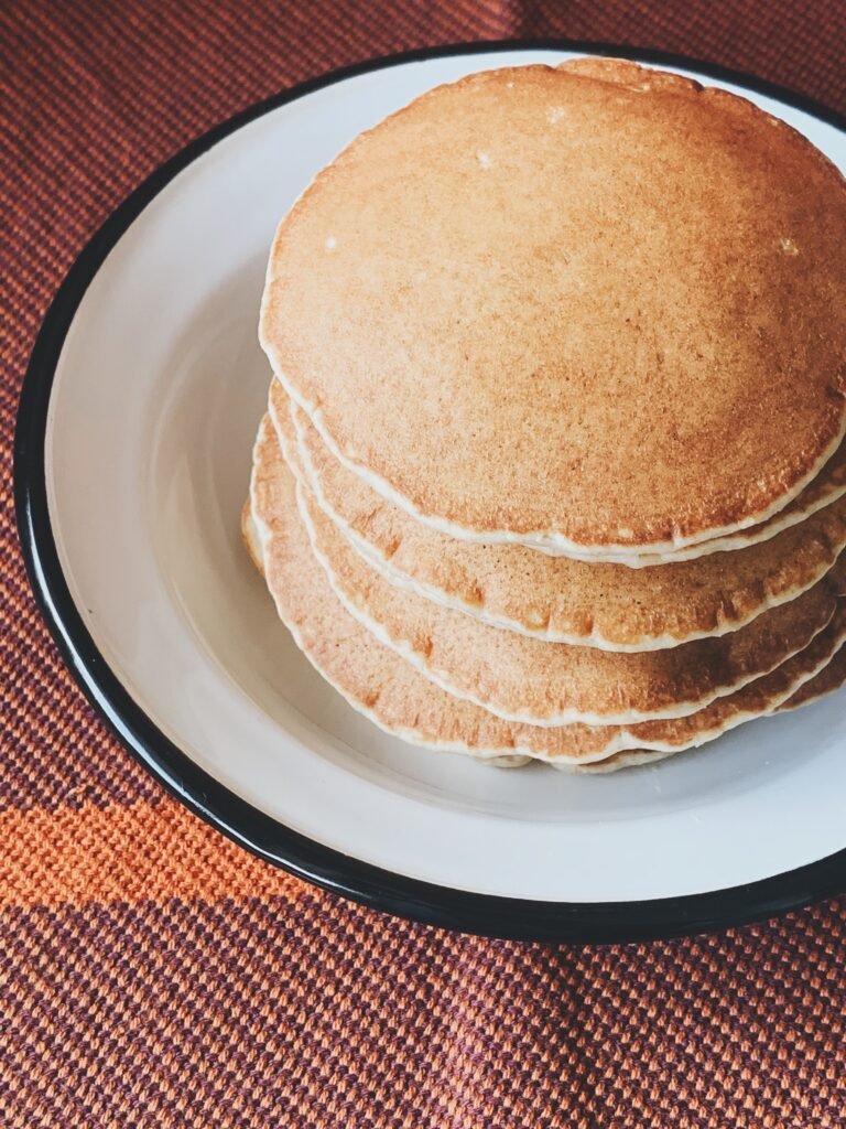 Close-up shot of golden pancakes on a white plate, perfect for a tasty breakfast.