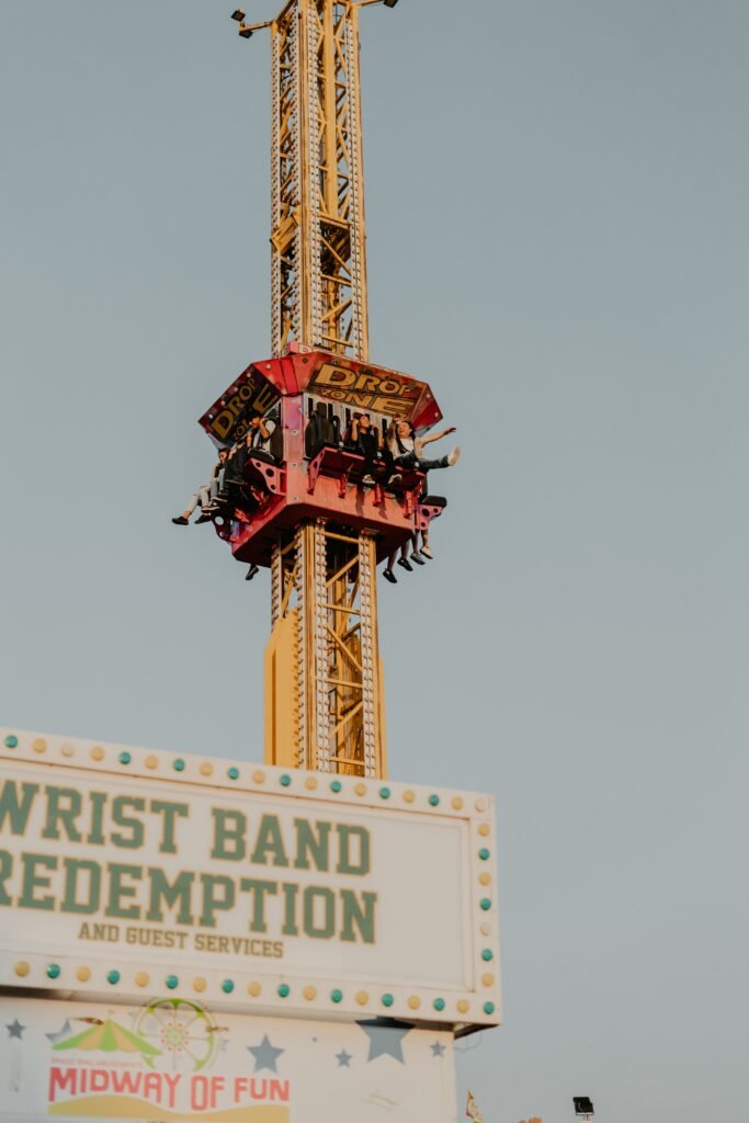 Experience the excitement of a drop tower ride at a vibrant fairground theme park.